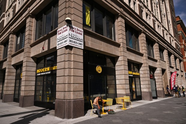A man sits at a table in front of a building that's available to lease on the 16th Street Mall in Denver on May 13, 2025. (Photo by Helen H. Richardson/The Denver Post)