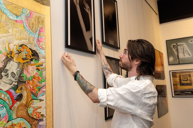 Jordan Slemmer, founder and director of Rainy Days Gallery, installs work by photographer Landry Luallen in the gallery on Thursday, July 3, 2025, in Denver. (Photo by Amanda Lopez/Special to The Denver Post)