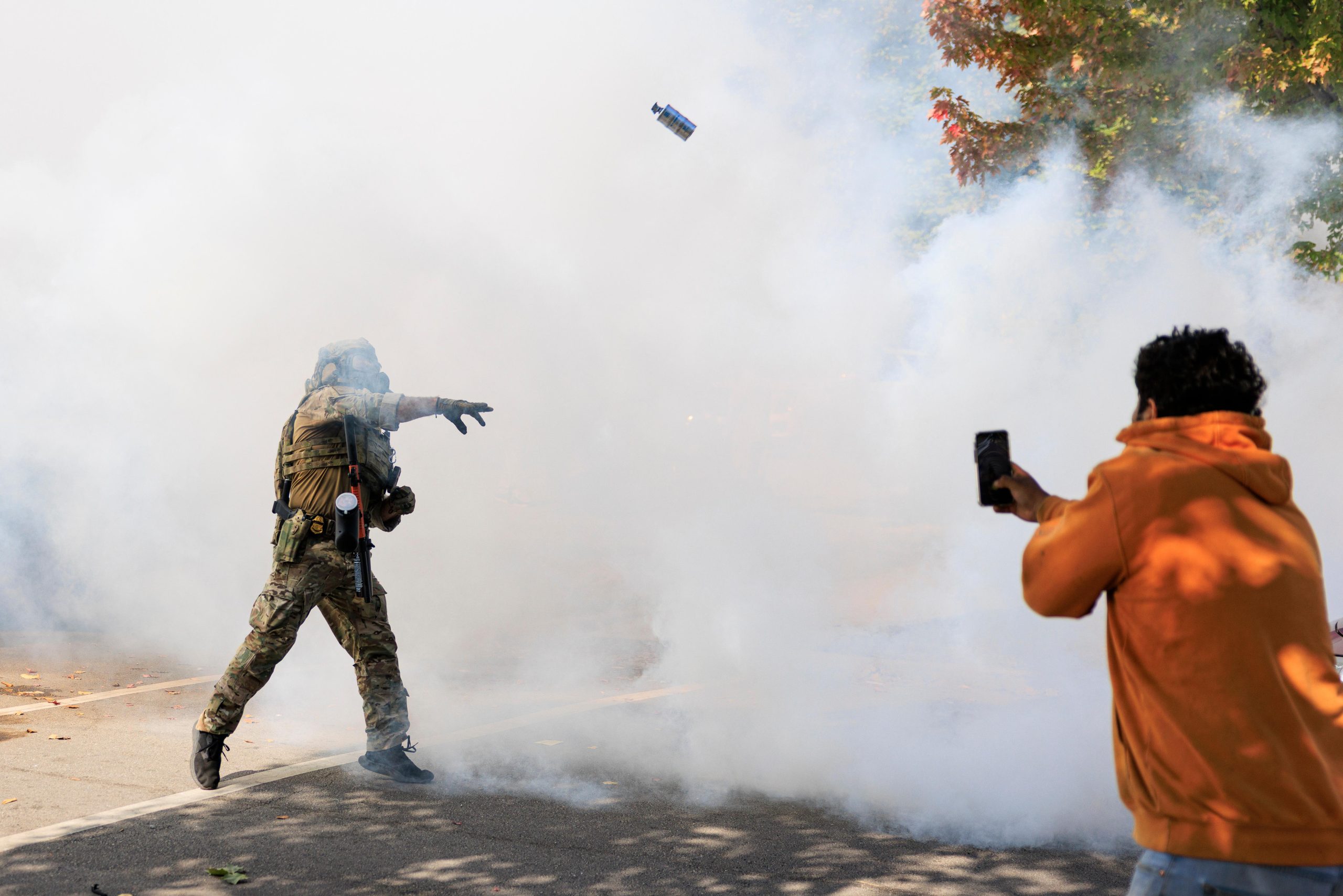 A government official throws a tear gas canister towards protesters...